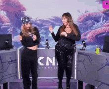 two women are dancing in front of a cn advertisement