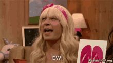 a man in a blonde wig is sitting on a couch holding a picture of flip flops .