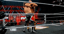 two wrestlers are hugging in a wrestling ring with a wwe logo in the background