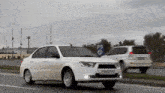 a white car with a license plate that says 99 fk 105 is driving down a road