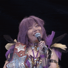 a woman with purple hair holds a microphone