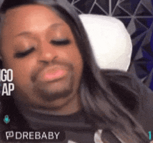 a man with a beard and long hair is laying on a bed with a pillow and a sign that says drebaby