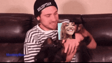 a man wearing a sleep team hat holds a small dog