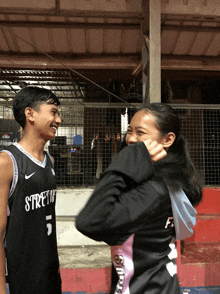 a boy wearing a jersey with the number 5 on it looks at a girl