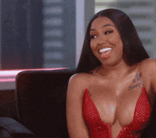 a woman with a tattoo on her arm is wearing a red dress and smiling