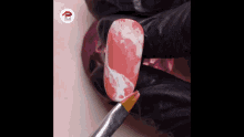 a person is painting a pink nail with a brush .