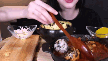 a woman is holding a wooden spoon over a bowl of food .