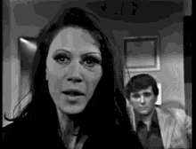 a black and white photo of a woman talking to a man in a suit .