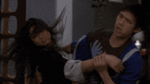 a man in a blue shirt is holding a woman 's arm