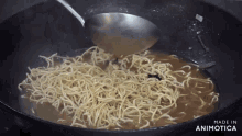 noodles are being stirred in a wok with the words made in animotica visible