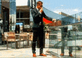 a man in a suit smoking a cigarette in front of a sign that says ' lrcs '