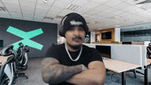 a man with his arms crossed wearing headphones and a beanie