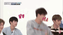 a group of young men are dancing in front of a white wall with korean writing on it .