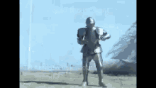 a man in a knight 's armor is standing in a field holding a sword .