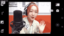 a woman wearing headphones stands in front of a microphone with the words honeycam.org on the bottom of the screen