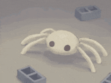 a white spider is sitting on a table next to a brick wall .