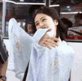 a woman covering her mouth with a white shirt and smiling