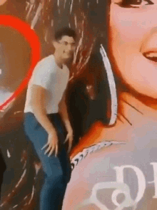 a man in a white shirt is dancing in front of a poster of a woman with the letter d on it