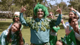 a group of people are dressed in green and giving the peace sign