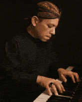 a man in a black shirt is playing a piano with a ring on his finger