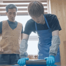 a man wearing blue gloves stands next to a man wearing a black shirt
