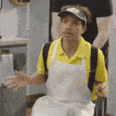 a man wearing a yellow shirt and an apron is holding a fork