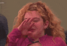 a woman with red hair is making a funny face with her eyes closed and her hair blowing in the wind .
