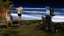 a man and woman are standing on a beach at night