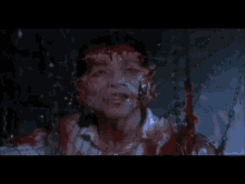 a person is hanging from chains in a dark room with blood coming out of them .