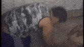 a man is doing push ups on the floor while wearing a camouflage tank top .