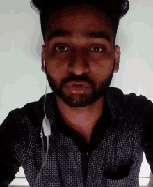 a man with a beard is wearing ear buds and making a funny face .
