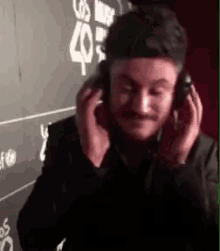a man wearing headphones is sitting in front of a sign that says los angeles 40 .