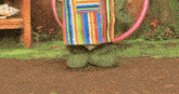 a green frog wearing a chef 's hat and apron is holding a pink hula hoop