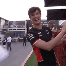 a man in a black and red shirt is giving a high five to someone .