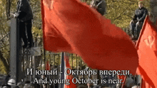 a crowd of people holding red flags with october near the bottom
