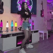 a woman is dancing in a living room with a tv in the background .