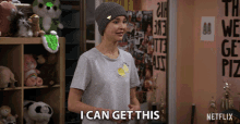 a girl in a beanie says " i can get this " in front of stuffed animals