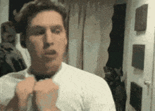 a man wearing a white shirt and a black bow tie is making a funny face