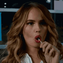 a woman is licking a lollipop in her mouth .