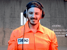 a man wearing headphones and an orange shirt has a patch on his chest that says eaeao