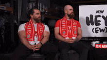two men sitting in front of a sign that says hey ( ew )