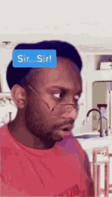 a man wearing glasses and a red shirt has a blue sticker on his head that says sir sir