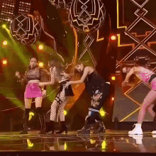 a group of women are dancing on a stage in front of a large screen .