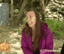 a woman in a purple jacket is sitting on a beach with the words @tvresidence above her