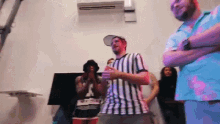a man in a striped shirt is standing in a room with other people