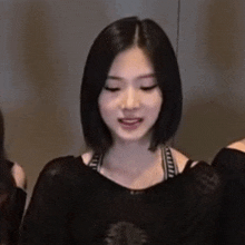 a young woman with short black hair is wearing a black shirt and a black bra .