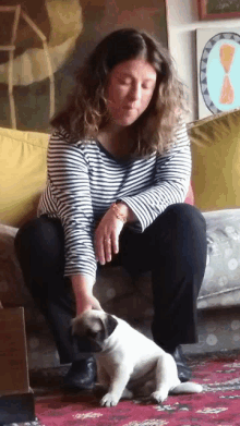 a woman sitting on a couch petting a small white dog