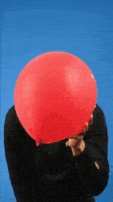 a person blowing up a red balloon with a blue background