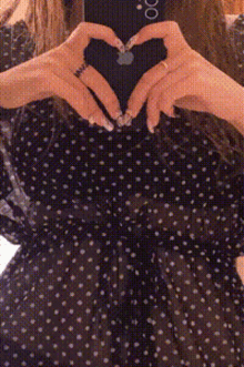 a woman is making a heart shape with her hands