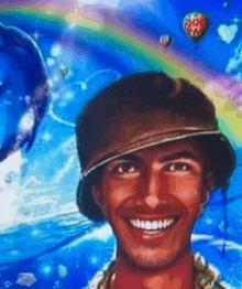 a man wearing a hat is smiling in front of a colorful background with hot air balloons .